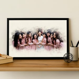 May include: A framed print in a watercolour style, depicting a group of women in pink and white outfits. The women are embracing each other. The print is in a black frame on a wooden surface.