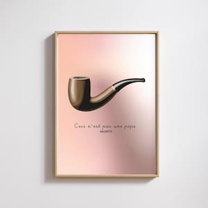 Op de afbeelding: Ingelijste kunstdruk met een bruine pijp met een zwarte steel tegen een roze gradiënt achtergrond. De tekst "Ceci n'est pas une pipe" en de naam van de kunstenaar, MAGRITTE, staan eronder.