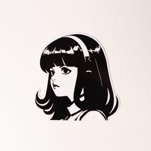 May include: A black and white die-cut sticker featuring a high-contrast graphic illustration of a person with shoulder-length hair, bangs, and a headband. The design uses bold black lines and solid black fill to depict the facial features.