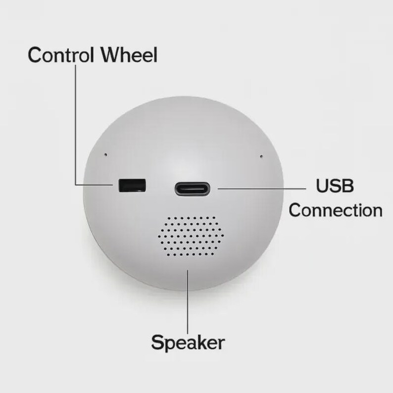 Puede incluir: Un dispositivo electr&oacute;nico esf&eacute;rico blanco con altavoz, conexi&oacute;n USB y rueda de control. El dispositivo tiene un dise&ntilde;o minimalista con las palabras "Control Wheel", "USB Connection" y "Speaker".