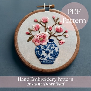 May include: Hand embroidery pattern featuring a blue and white vase with pink flowers. The design is set in a wooden embroidery hoop. Text on the image reads "PDF Pattern" and "Hand Embroidery Pattern Instant Download."