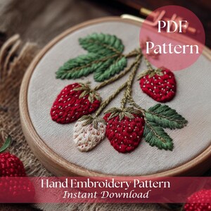 Peut inclure: Motif de broderie à la main représentant des fraises. L'image montre un tissu beige tendu dans un cercle à broder en bois. Les fraises sont rouges et blanches, avec des feuilles et des tiges vertes. Le texte "PDF Pattern" et "Hand Embroidery Pattern Instant Download" est visible.
