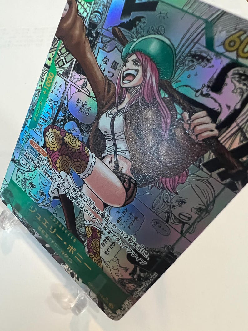 Puede incluir: Una tarjeta coleccionable hologr&aacute;fica con una ilustraci&oacute;n de personaje. El personaje es una mujer con cabello rosado, que lleva un sombrero verde, una chaqueta marr&oacute;n y una blusa blanca. La tarjeta tiene texto japon&eacute;s y un contador +1000.