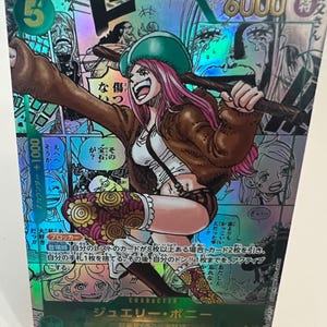 Puede incluir: Carta coleccionable hologr&aacute;fica con Jewelry Bonney de One Piece. La carta tiene un fondo verde con texto japon&eacute;s y una ilustraci&oacute;n de un personaje de una mujer con cabello rosado, que lleva una chaqueta marr&oacute;n y un sombrero verde.