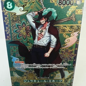 May include: A trading card featuring a character illustration of a man in a black hat and coat, holding a sword. The card has a green and gold patterned background with Japanese text and the number 8 and 8000. The character is named "Juraquille Mihawk".