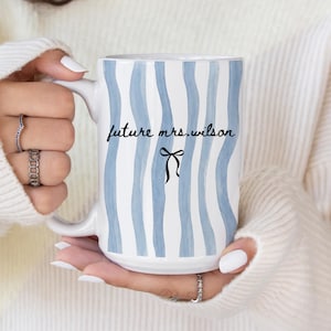 May include: A set of three ceramic mugs with a speckled, matte finish. The mugs are in shades of cream, light gray, and dark gray. Each mug has a simple, minimalist design, perfect for coffee or tea.