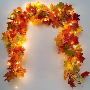 May include: A fall-themed garland featuring maple leaves in shades of red, orange, and yellow. The garland is illuminated with small, warm white LED lights, creating a festive and inviting ambiance. Perfect for autumn decor.
