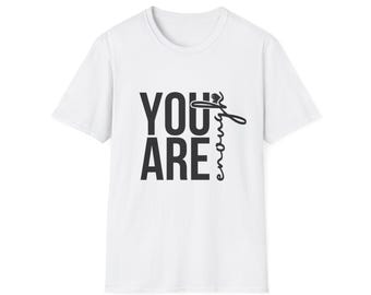 以下が含まれることがあります： 太字の黒いフォントで「YOU ARE」という言葉が重ねられた白いTシャツ。「enough」という単語は、「YOU ARE」の右側に筆記体の黒いフォントで書かれています。