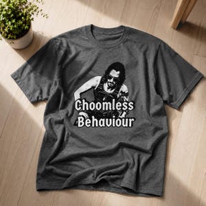 May include: Dark grey t-shirt with a black and white graphic of a person wearing sunglasses and the text "Choomless Behaviour". The shirt is made of a soft material and has a crew neck.