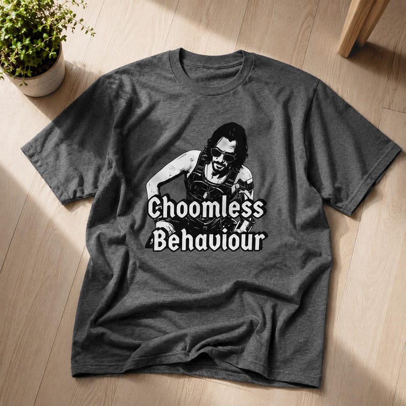 May include: Dark grey t-shirt with a black and white graphic of a person wearing sunglasses and the text "Choomless Behaviour". The shirt is made of a soft material and has a crew neck.