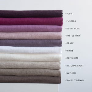 May include: A stack of linen fabric in various colors, including plum, fuchsia, dusty rose, pastel pink, grape, white, off-white, natural light, natural, and walnut brown. The colors are labeled on the right side of the image.