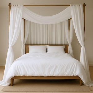 May include: A wooden four-poster bed with white bedding and sheer white curtains draped around the frame. The bed has a light brown wooden frame and a neutral-coloured rug underneath.