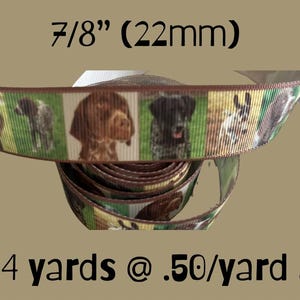 May include: A roll of decorative ribbon featuring a repeating pattern of dog portraits. The ribbon is 7/8 inch (22mm) wide and has a brown border. The background is a tan color.