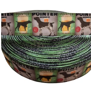 May include: A roll of decorative ribbon featuring a repeating pattern. The pattern includes images of a dog, a beer glass, and the text "POINTER BREWING CO." in green, brown, and white. The ribbon has a green and black striped edge.