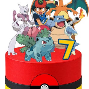 Peut inclure: Une décoration de gâteau cylindrique avec le nom Enea en lettres jaunes, un personnage de dessin animé et plusieurs créatures dont un Bulbizarre bleu, un dragon orange ailé et une tortue bleue. Un grand chiffre 7 jaune et une Poké Ball.