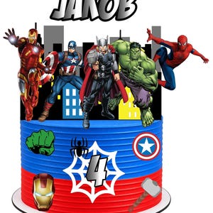 Op de afbeelding: Een cilindrische taarttopper met de naam JAKOB in vetgedrukte letters boven illustraties van Iron Man, Captain America, Thor, Hulk en Spider-Man. De basis is blauw en rood met iconen van een vuist, spin, schild, masker, hamer en het cijfer 4.