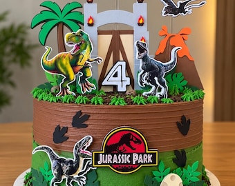 May include: A round cake with brown and green frosting, decorated with dinosaur-themed toppers including a T-Rex, raptors, a volcano, a palm tree, a gate, a Jurassic Park logo, and a cutout reading CARLOS with the number 4.