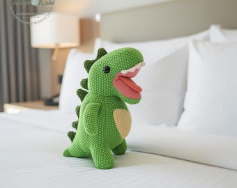 Peluche verte faite main de dinosaure au crochet avec des pointes et la langue rose