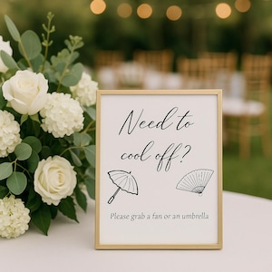 May include: A framed sign with the text "Need to cool off?" in elegant script, along with illustrations of an umbrella and a fan. The sign also includes the text "Please grab a fan or an umbrella."