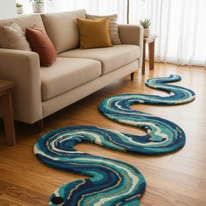 Könnte beinhalten: Ein Teppich in Schlangenform mit Kopf und langem, gewundenem Körper. Der Teppich hat ein Muster aus blauen, türkisfarbenen und weißen Wirbeln mit goldenen Akzenten. Er liegt auf einem Holzboden in einem Wohnzimmer.