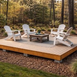 May include: An outdoor seating area with a wooden deck, four white Adirondack chairs, and a square wooden coffee table. The deck is set on a bed of mulch and surrounded by trees in a natural setting.