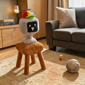 Può includere: Uno sgabello a forma di robot in peluche con una testa grigia, un corpo marrone e quattro gambe marroni. Il robot ha una faccia a schermo nero con una bocca sorridente e un cappello con elica colorata. Lo sgabello è su un tappeto beige. Il testo "SnugglePlayCo" è visibile.
