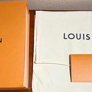 May include: An orange box and a white dust bag, both with the words "LOUIS VUITTON" printed in black. A small orange card with the brand name is also visible.