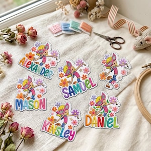 May include: Six embroidered patches featuring a cartoon character wearing pink sunglasses, surrounded by colorful flowers. Each patch displays a unique name: Alexander, Samuel, Mason, Kinsley, and Daniel, with one patch showing only the character.