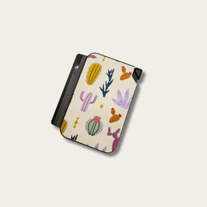May include: A cream-colored phone case featuring a colorful cactus pattern. The design includes yellow, purple, orange, and green cacti and succulents. The case has a black border and a black magnetic closure.