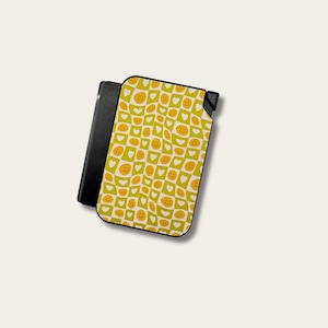 May include: A black lighter with a yellow and white patterned cover. The cover features a repeating design of smiley faces and hearts on a checkered background. The lighter is rectangular and has a hinged top.