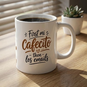 Puede incluir: Una taza de cerámica blanca llena de café oscuro, con el texto impreso en marrón y negro First mi Cafecito then los emails y un pequeño icono de corazón en el centro. La taza tiene un asa curva y un acabado liso y brillante.