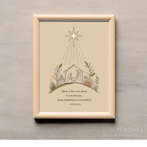 Puede incluir: Una lámina decorativa enmarcada sobre fondo beige con un dibujo lineal de un belén bajo una gran estrella. El texto dice: ¡Gloria a Dios en las alturas, Y en la tierra paz, buena voluntad para con los hombres! – LUCAS 2:14. El marco es de madera clara.