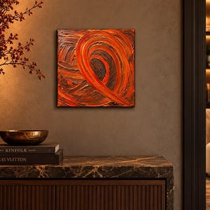 May include: A square abstract painting featuring thick, textured impasto brushstrokes in shades of vibrant orange, deep red, and dark brown. The composition displays a prominent swirling motion with a signature visible in the bottom right corner.
