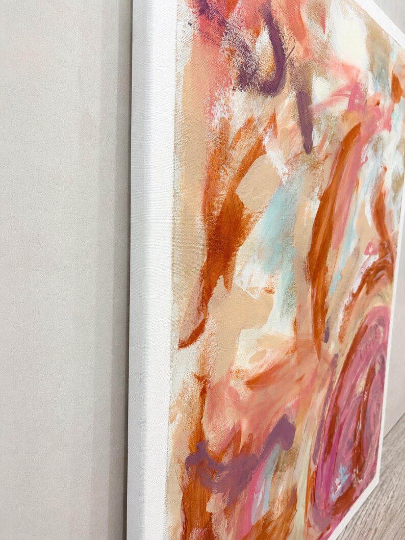 May include: An abstract painting on a rectangular canvas featuring thick, expressive brushstrokes in shades of burnt orange, soft pink, cream, and deep purple. The paint texture is visible across the surface, framed by a clean white border.