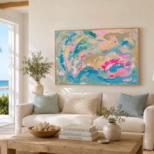 May include: A large rectangular abstract painting featuring vibrant swirls of turquoise, bright pink, soft peach, and metallic gold paint. The artwork is displayed in a thin, light-toned wooden frame, showcasing expressive, layered brushstrokes.