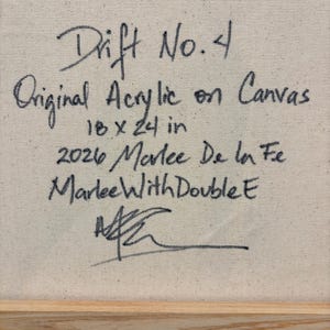 May include: The back of a canvas featuring black handwritten text that reads: Drift No. 4, Original Acrylic on Canvas, 18 x 24 in, 2026 Marlee De la Fe, MarleeWithDoubleE, and a signature. A light-colored wooden frame edge is visible at the bottom.