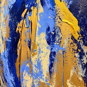 May include: An abstract painting on canvas featuring thick, textured layers of deep navy blue, bright royal blue, and metallic gold paint. The composition displays heavy impasto brushstrokes and splatters, creating a dynamic surface.