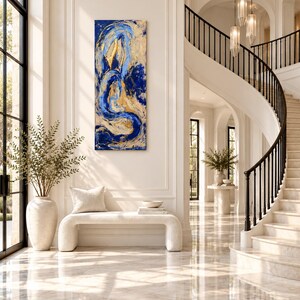 May include: A vertical rectangular canvas painting featuring abstract swirls of deep blue and metallic gold paint. The artwork displays thick, textured brushstrokes that create a dynamic, flowing composition across the entire surface.