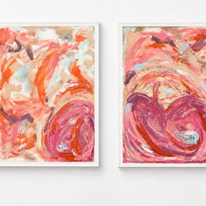 May include: Two framed abstract paintings featuring thick, expressive brushstrokes in shades of coral, magenta, deep red, and soft beige. The compositions display swirling, layered textures with visible paint marks and light blue accents.