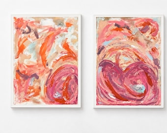 May include: Two framed abstract paintings featuring thick, expressive brushstrokes in shades of coral, magenta, deep red, and soft beige. The compositions display swirling, layered textures with visible paint marks and light blue accents.