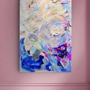 Op de afbeelding: Een abstract schilderij op een rechthoekig canvas met een dynamische compositie van gelaagde penseelstreken in tinten helderblauw, diepviolet, zacht perzik, cr&egrave;me en metallic goud, wat zorgt voor een getextureerde en vloeiende beweging.