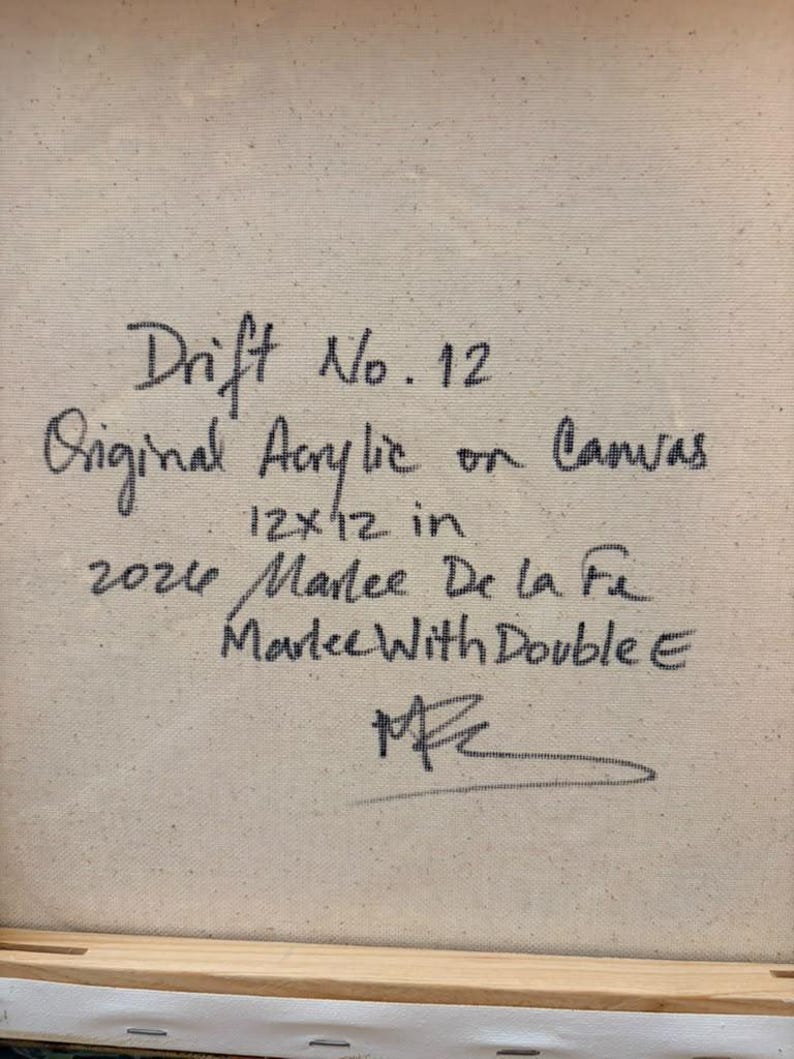 May include: A square canvas back featuring black handwritten text that reads: Drift No. 12, Original Acrylic on Canvas, 12x12 in, 2024, Marlee De la Fe, Marlee With Double E, and a signature. The canvas is mounted on a light wood frame.
