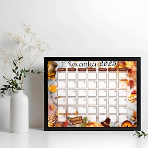 Peut inclure: Calendrier encadré de novembre 2025 sur le thème de l'Action de grâce. Le calendrier a un cadre noir et présente un fond en marbre avec des feuilles d'automne, des citrouilles et un chapeau de pèlerin. Le texte "Thanksgiving" est visible.