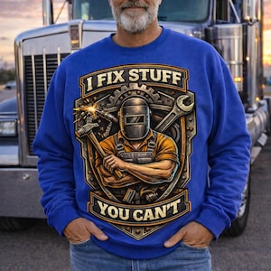 May include: Royal blue sweatshirt with the text "I FIX STUFF YOU CAN'T" and a graphic of a welder with tools. The design features a hammer, wrench, and welding mask. The person is wearing blue jeans and standing in front of a semi-truck.