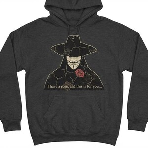 May include: Dark gray hoodie featuring a graphic of a stylized figure wearing a hat and mask, holding a rose. The text "I have a rose, and this is for you..." is printed below the graphic.