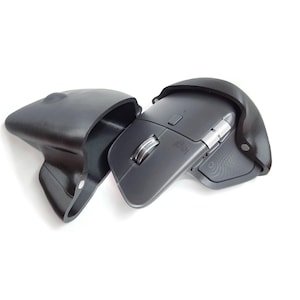 May include: A dark grey wireless computer mouse with a black carrying case. The mouse features a scroll wheel and several buttons. The open carrying case displays the mouse. The mouse and case are set against a white backdrop.