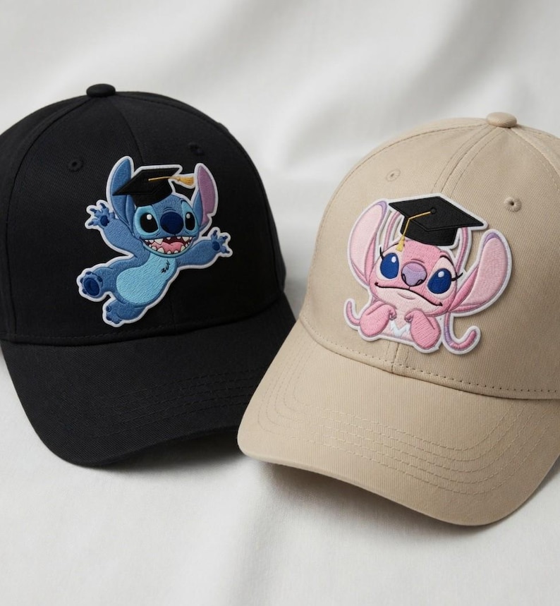 Puede incluir: Dos gorras de b&eacute;isbol con personajes de dibujos animados bordados. Una es negra con un personaje azul que lleva un birrete. La otra es beige con un personaje rosa que lleva un birrete. Ambas gorras tienen una visera curva.