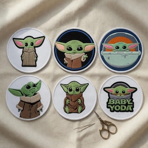 Puede incluir: Colección de seis parches bordados circulares con el personaje Baby Yoda de Star Wars. Cada parche muestra un diseño diferente del personaje, con piel verde, orejas grandes y una capa marrón. También hay unas tijeras pequeñas y unas pinzas.