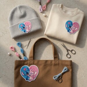 May include: A light gray beanie, cream-colored sweatshirt, and brown tote bag, each adorned with a heart-shaped patch featuring blue and pink cartoon characters. Embroidery floss, needles, and scissors are also present.
