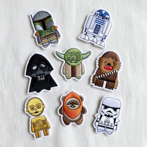 May include: A collection of eight embroidered patches featuring characters from the Star Wars franchise. The patches include Boba Fett, R2-D2, Darth Vader, Yoda, Chewbacca, C-3PO, an Ewok, and a Stormtrooper. Each patch has a white border.